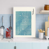 Plakat med blå og hvidt design af svaner på vandet, placeret i en moderne køkkenindretning.