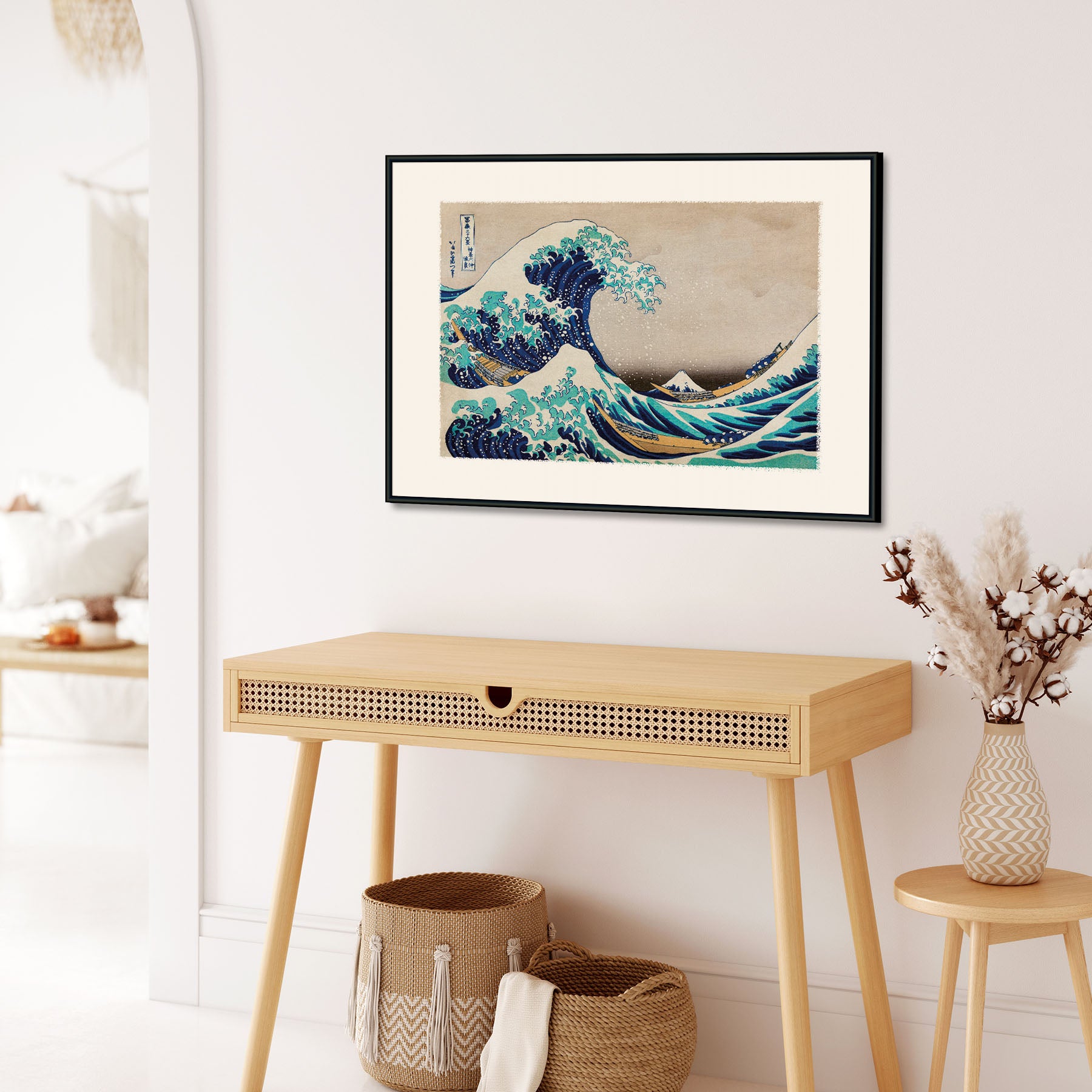 Plakat af "The Great Wave" af Katsushika Hokusai hængende på en væg over et træbord i et stilfuldt rum.