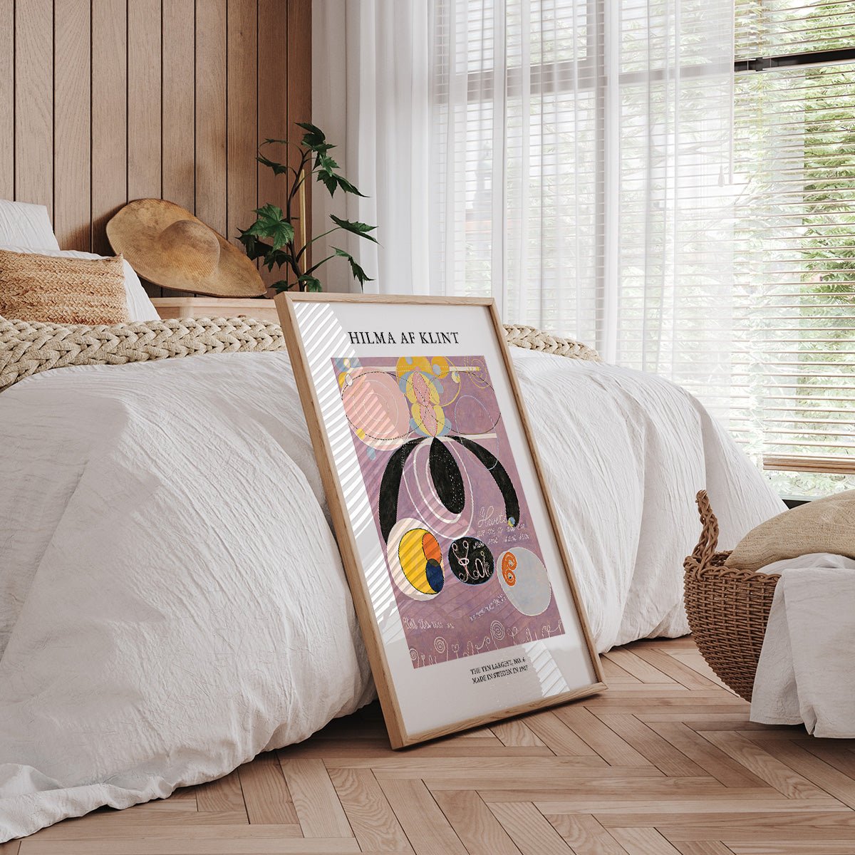 Hilma af Klint plakat i soveværelse med hvidt sengetøj og træpaneler.