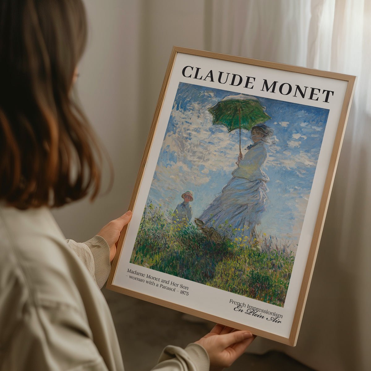 Person holder indrammet Claude Monet plakat af kvinde og barn på mark