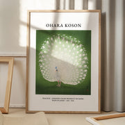 Ohara Koson Peacock plakat i egetræsramme på gulv i stue. Solstråler skinner på plakaten. 