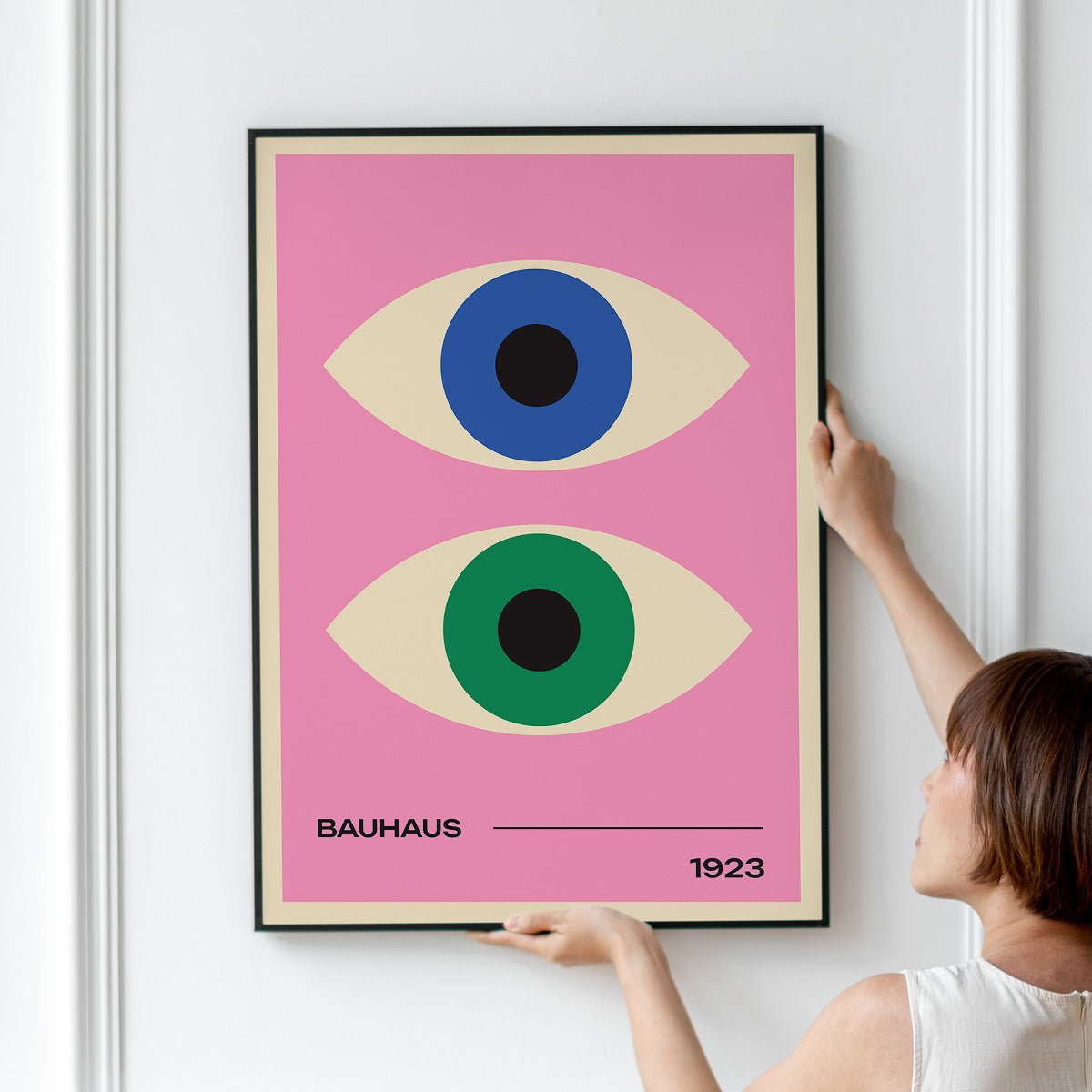 Plakat med to stiliserede øjne i blå og grøn på en lyserød baggrund, med teksten "Bauhaus 1923".