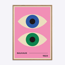Bauhaus plakat med to stiliserede øjne i blå og grøn på en lyserød baggrund, indrammet i naturtræ.