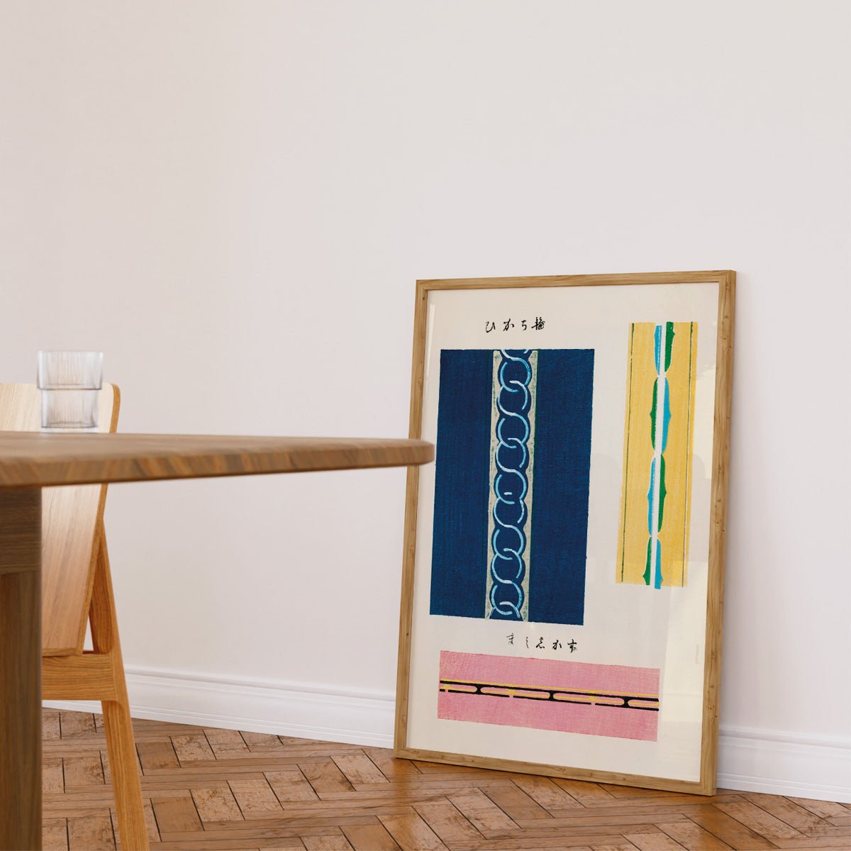 Plakat med farverige japanske mønstre, lænet mod en hvid væg i et lyst rum.