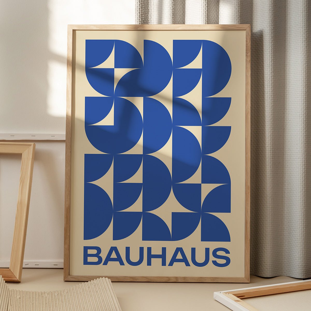 Bauhaus plakat med blå geometriske former på gulv med vinduesskygge