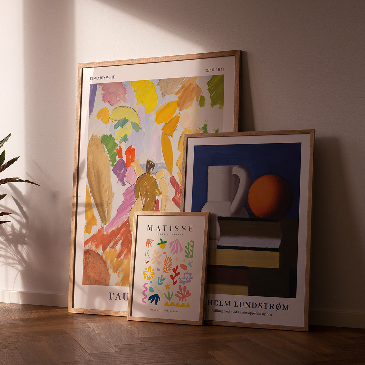 3 plakater "Faun og Nymfe" af Edvard Weie, "Matisse Modern Gallery" og Vilhelm Lundstrøm plakat på trægulv i stue. Plakaterne er i lys egetræsramme.