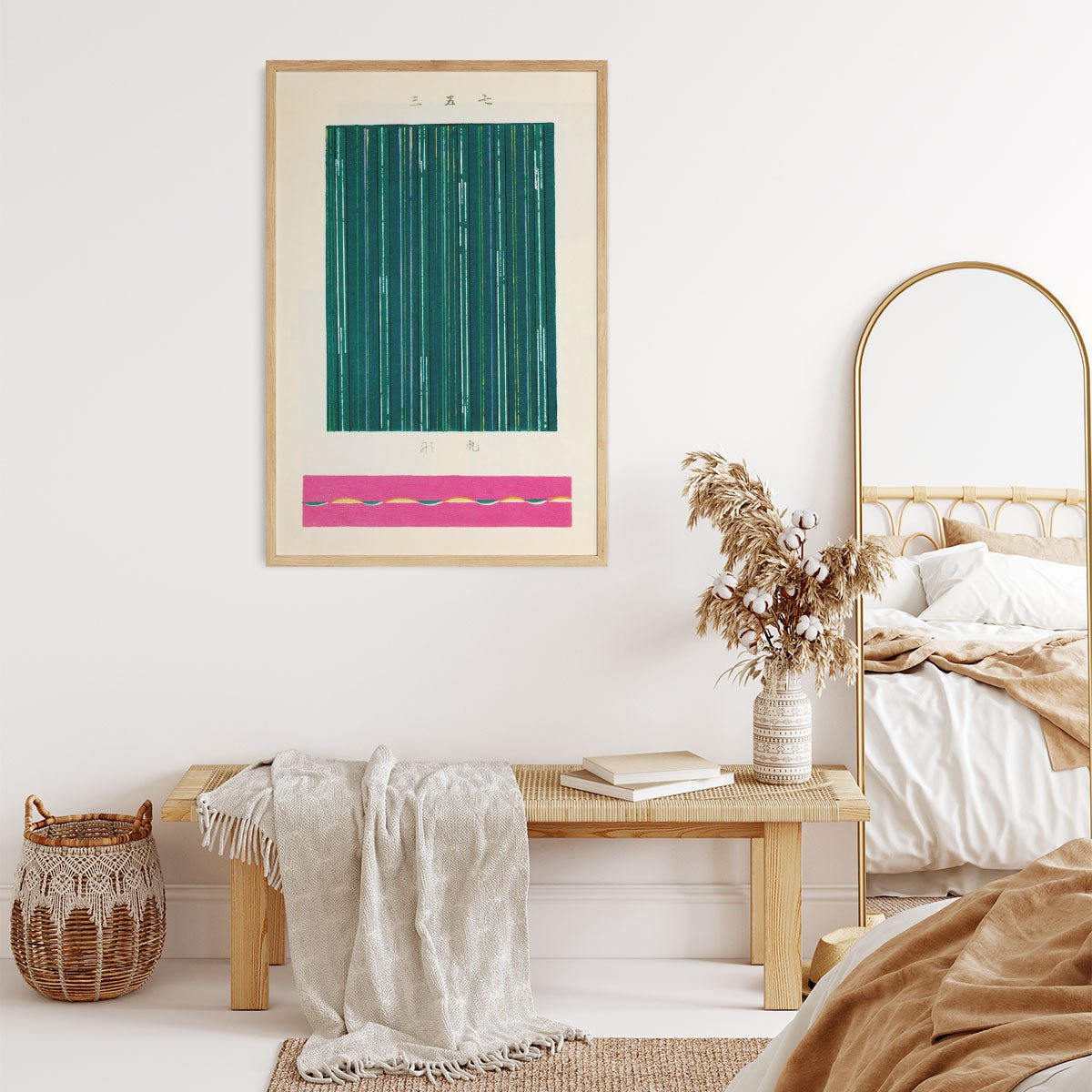 Plakat med abstrakt design i grønne og pink nuancer, hængende på en væg i et stilfuldt indrettet rum med en bænk, tæppe og kurv.