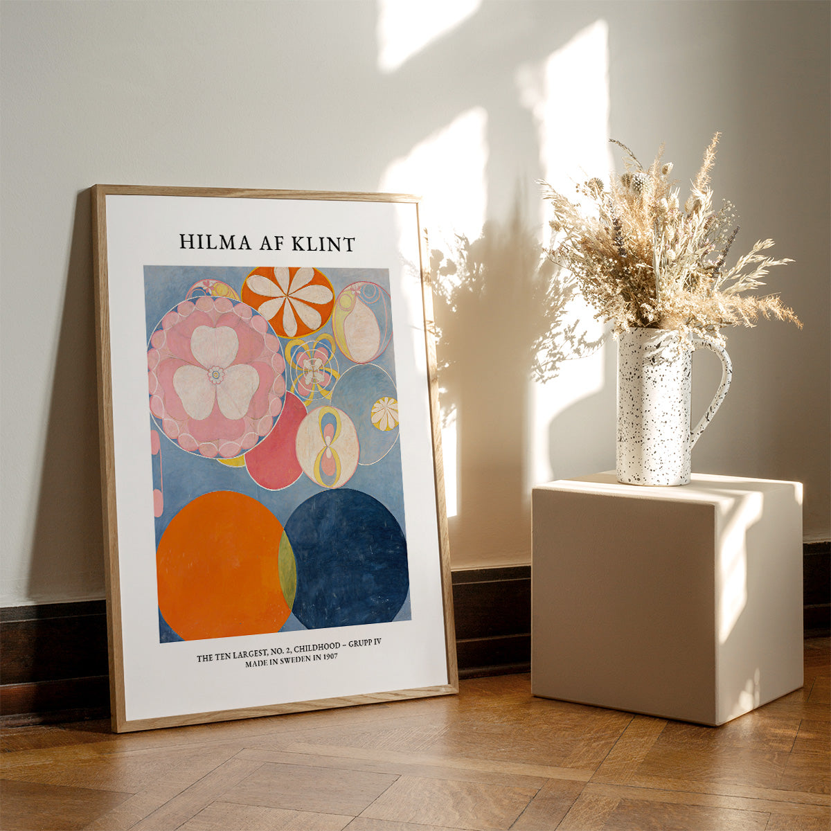 Plakat af Hilma af Klint med titlen "No. 2 Childhood" placeret på gulvet ved siden af en vase med tørrede blomster.